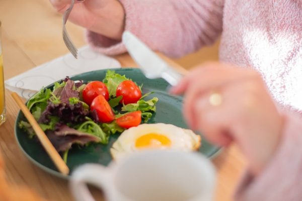 Enjoy a nutritious breakfast with greens, fried egg, and fresh orange juice for a healthy start to your day.